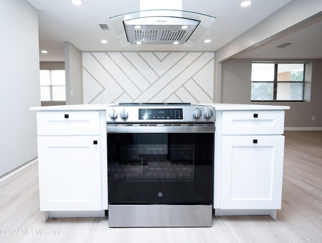 kitchen with white cabinets, light wood-type flooring, stainless steel electric range oven, and extractor fan