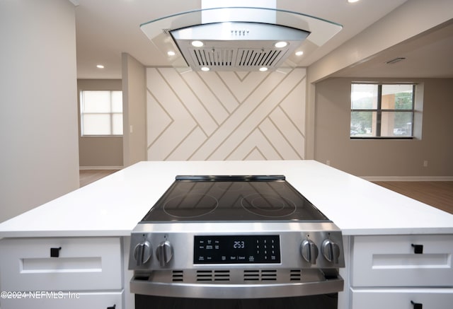 kitchen featuring white cabinets, island exhaust hood, and stainless steel range oven