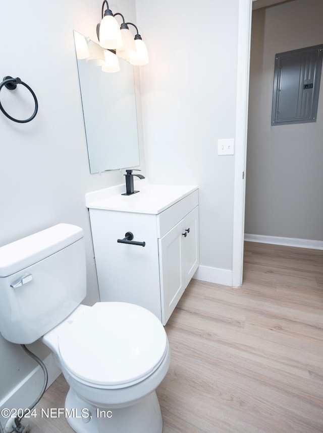 bathroom with hardwood / wood-style flooring, vanity, toilet, and electric panel