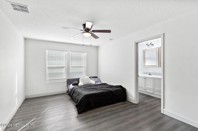 bedroom featuring a textured ceiling, ceiling fan, dark wood-type flooring, and ensuite bath