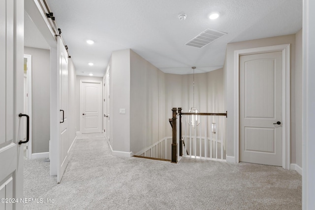 corridor featuring a barn door and light carpet