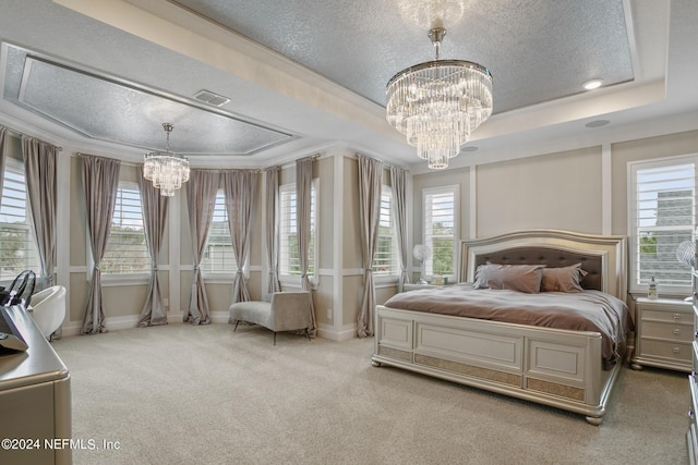 carpeted bedroom with a raised ceiling, multiple windows, and a notable chandelier