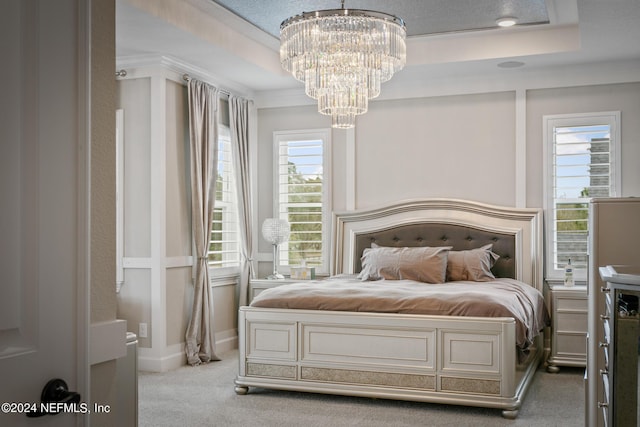 carpeted bedroom with a raised ceiling, crown molding, and an inviting chandelier