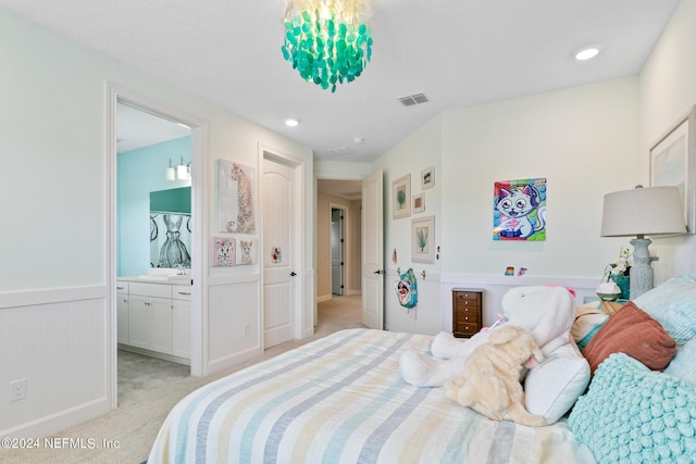 bedroom featuring light colored carpet and ensuite bath