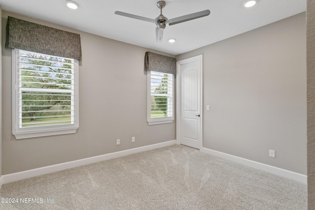 spare room with ceiling fan and light colored carpet