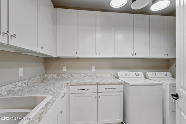 clothes washing area featuring sink, washing machine and dryer, and cabinets