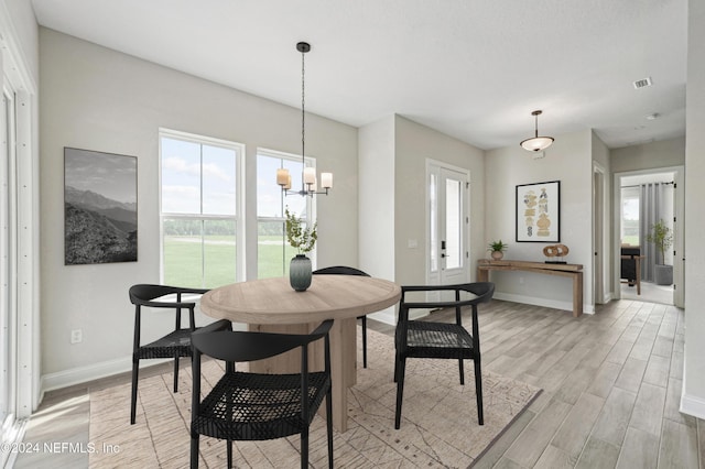 dining room with light hardwood / wood-style floors and a notable chandelier