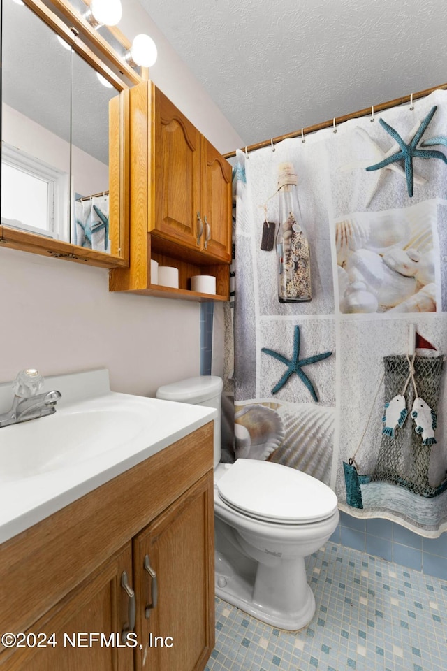 bathroom featuring tile patterned floors, vanity, a textured ceiling, and toilet