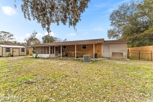 rear view of property with cooling unit, a shed, a yard, and a patio area