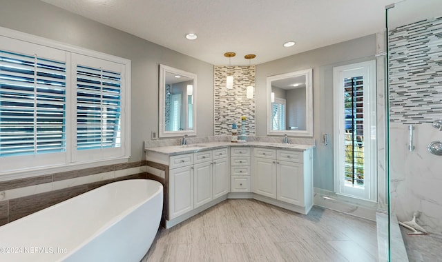 bathroom featuring plus walk in shower, a textured ceiling, vanity, and tile walls