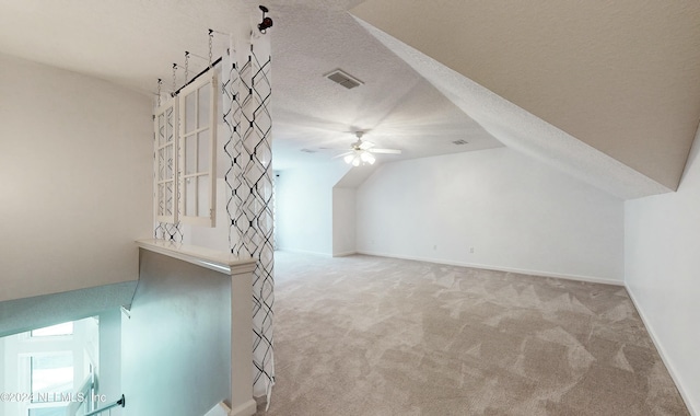 additional living space with a textured ceiling, ceiling fan, light carpet, and lofted ceiling