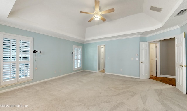 carpeted spare room with a raised ceiling, ceiling fan, and ornamental molding