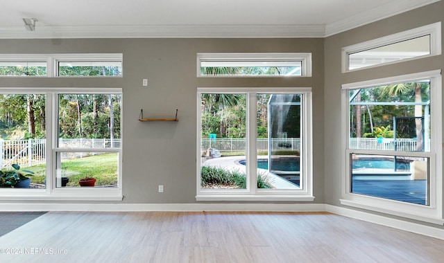 doorway to outside with a wealth of natural light, wood-type flooring, and ornamental molding