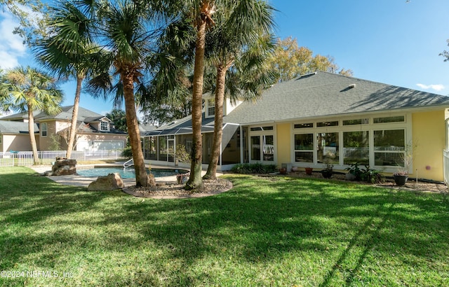 rear view of house with a fenced in pool and a yard