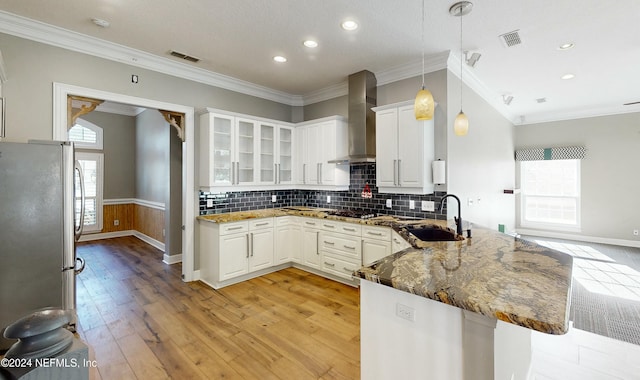 kitchen with white cabinetry, stainless steel appliances, wall chimney range hood, kitchen peninsula, and crown molding