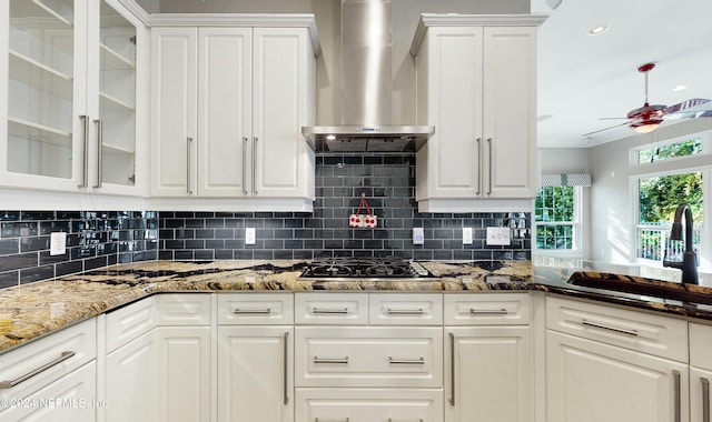 kitchen featuring white cabinets, backsplash, wall chimney exhaust hood, and sink