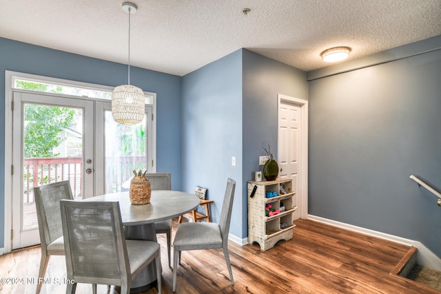 dining space featuring dark hardwood / wood-style flooring, french doors, a textured ceiling, and an inviting chandelier