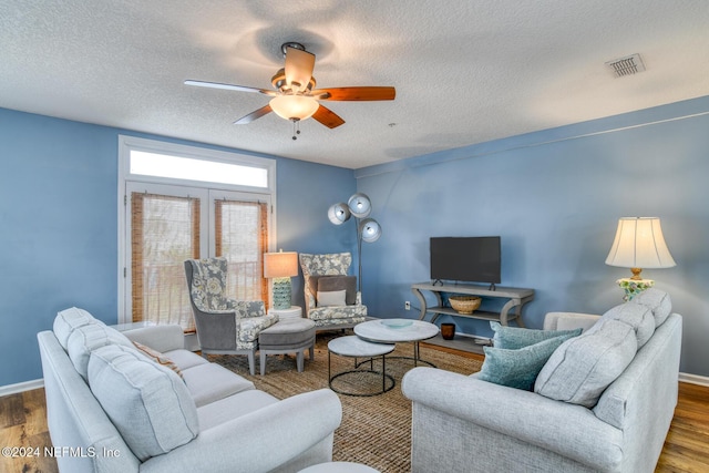 living room with a textured ceiling, hardwood / wood-style flooring, and ceiling fan