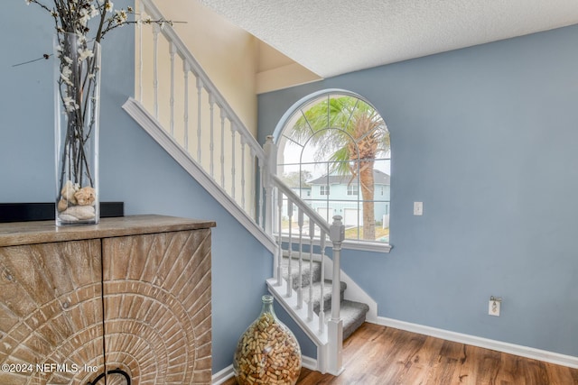 staircase featuring a textured ceiling and hardwood / wood-style flooring