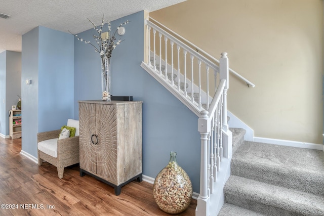 staircase with a textured ceiling and hardwood / wood-style flooring