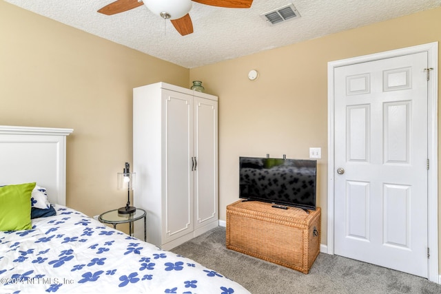 carpeted bedroom featuring ceiling fan and a textured ceiling