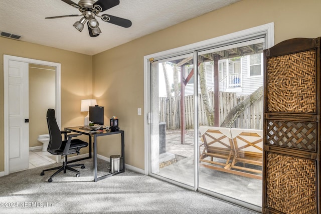 carpeted office space with a textured ceiling and ceiling fan