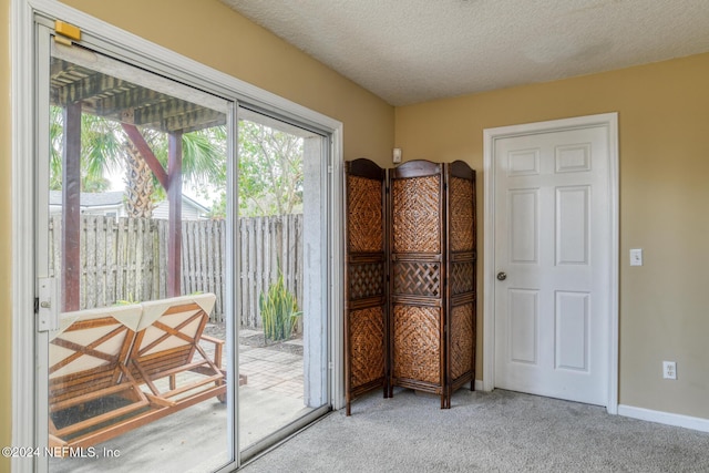 doorway to outside with carpet floors and a textured ceiling