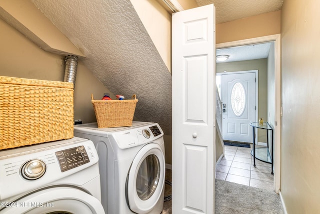 laundry area featuring washing machine and dryer, light tile patterned floors, and a textured ceiling