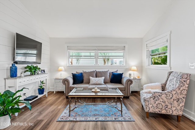 living room with dark wood-type flooring, a wealth of natural light, and lofted ceiling