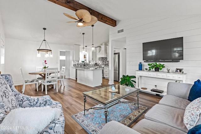 living room with vaulted ceiling with beams, dark hardwood / wood-style floors, wood walls, and ceiling fan