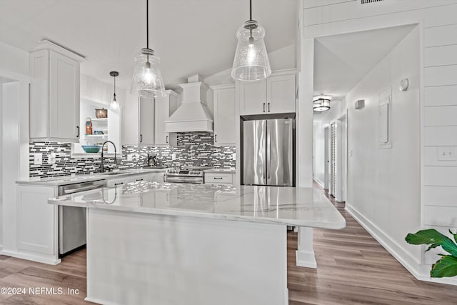 kitchen with custom exhaust hood, a center island, white cabinets, light wood-type flooring, and stainless steel appliances