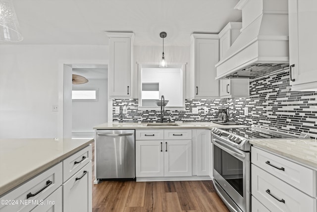 kitchen featuring pendant lighting, premium range hood, dark wood-type flooring, appliances with stainless steel finishes, and white cabinetry