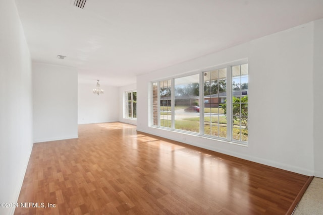 unfurnished room featuring an inviting chandelier and light hardwood / wood-style flooring