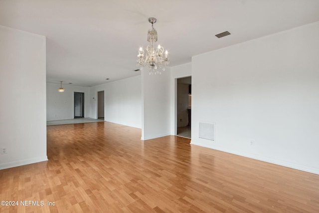 unfurnished room featuring a chandelier and light hardwood / wood-style floors