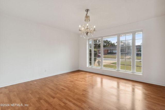 unfurnished room with a notable chandelier and light hardwood / wood-style floors