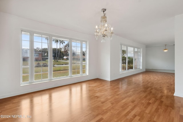 unfurnished dining area with a notable chandelier, hardwood / wood-style flooring, and plenty of natural light