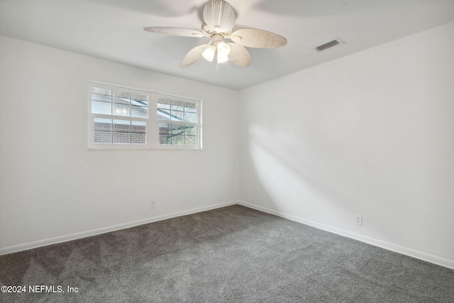 empty room featuring ceiling fan and dark carpet