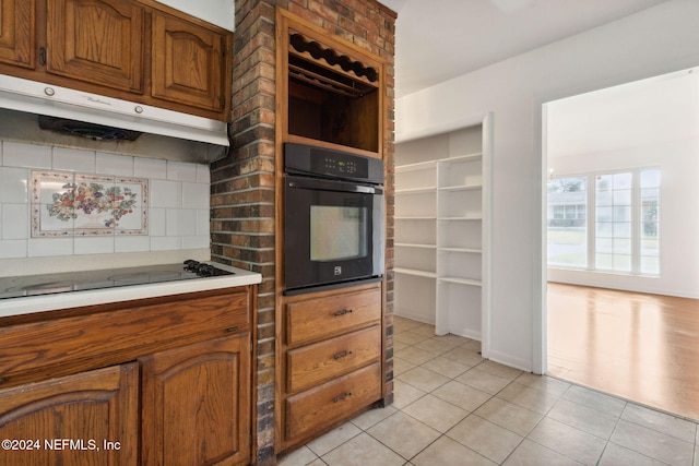 kitchen with light tile patterned flooring, decorative backsplash, and black appliances