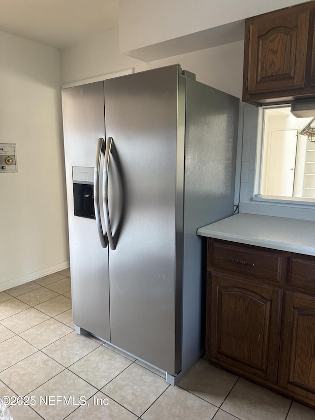 kitchen featuring dark brown cabinetry, stainless steel fridge, and light tile patterned floors