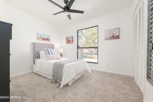 bedroom with carpet flooring, ceiling fan, a closet, and a textured ceiling