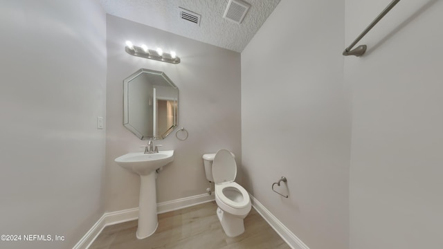 bathroom featuring a textured ceiling, toilet, and sink