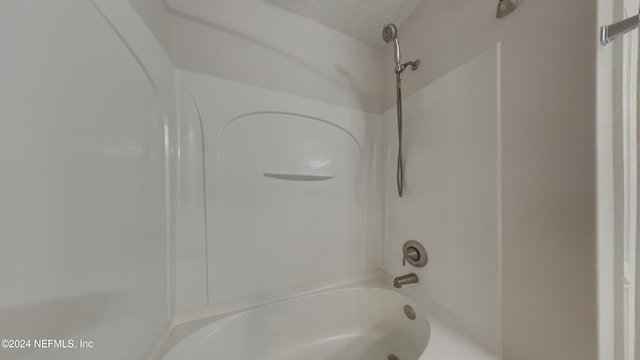 bathroom with  shower combination and a textured ceiling