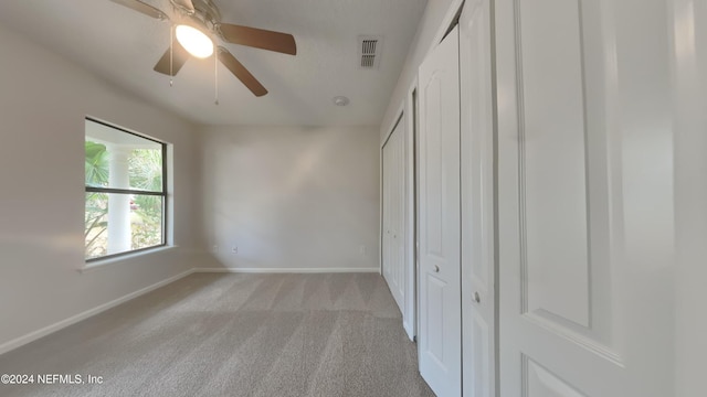 unfurnished bedroom with light colored carpet and ceiling fan