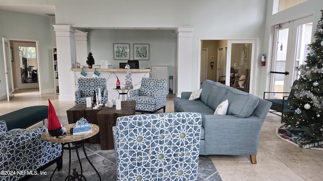 living room featuring decorative columns, plenty of natural light, and french doors