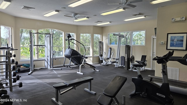 exercise room with ceiling fan and a textured ceiling