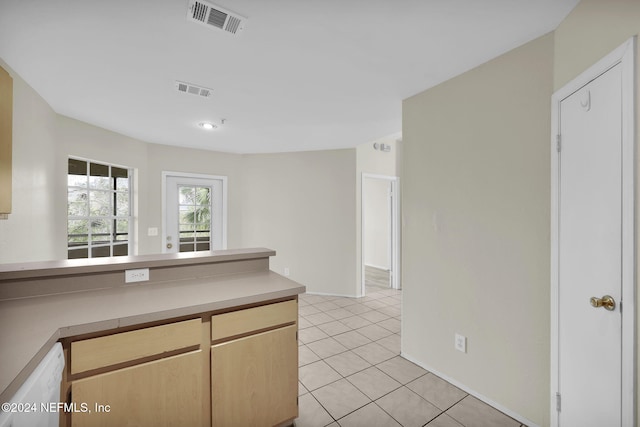 kitchen featuring white dishwasher, light tile patterned floors, and light brown cabinets