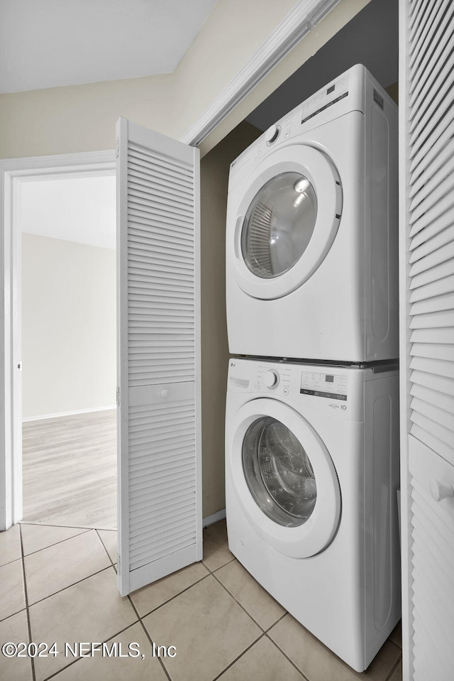 laundry area featuring stacked washing maching and dryer and light tile patterned floors