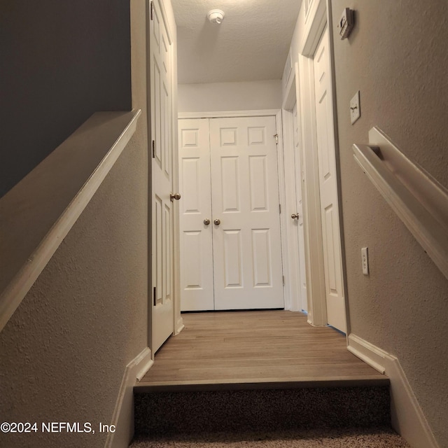 staircase featuring a textured ceiling and hardwood / wood-style flooring