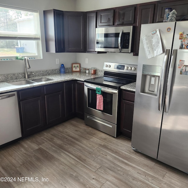 kitchen featuring dark brown cabinetry, stainless steel appliances, light hardwood / wood-style flooring, and sink