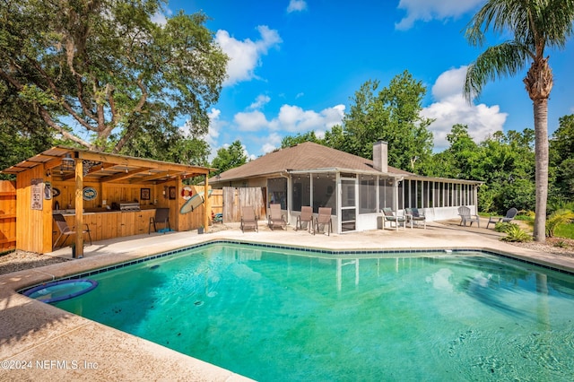 view of pool with a patio area, a sunroom, and exterior bar